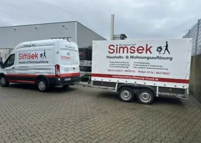 Transportfahrzeug von Simsek für Haushalts- und Wohnungsauflösungen, ausgestattet mit einem Anhänger, auf einem gepflasterten Platz.
